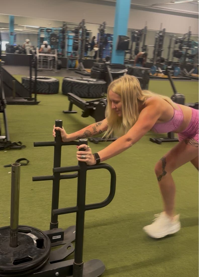 A team member pushing a weighted sled during a morning gym session