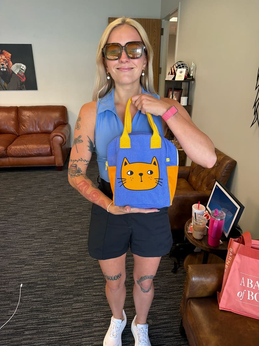 A team member in the office holding up a tote bag